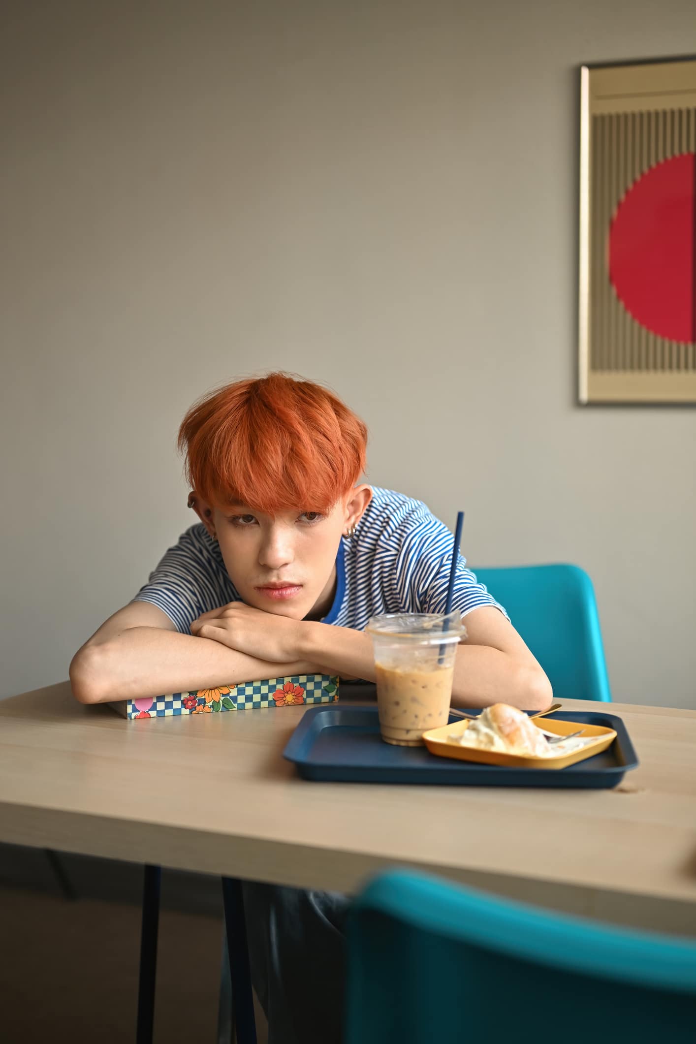 teenage boy with bright colored hair looking bored when take a nap on the book.