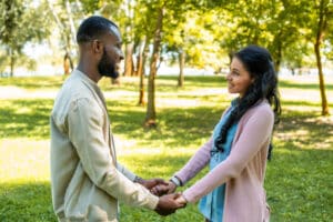 smiling african american couple holding hands and looking at each other in park