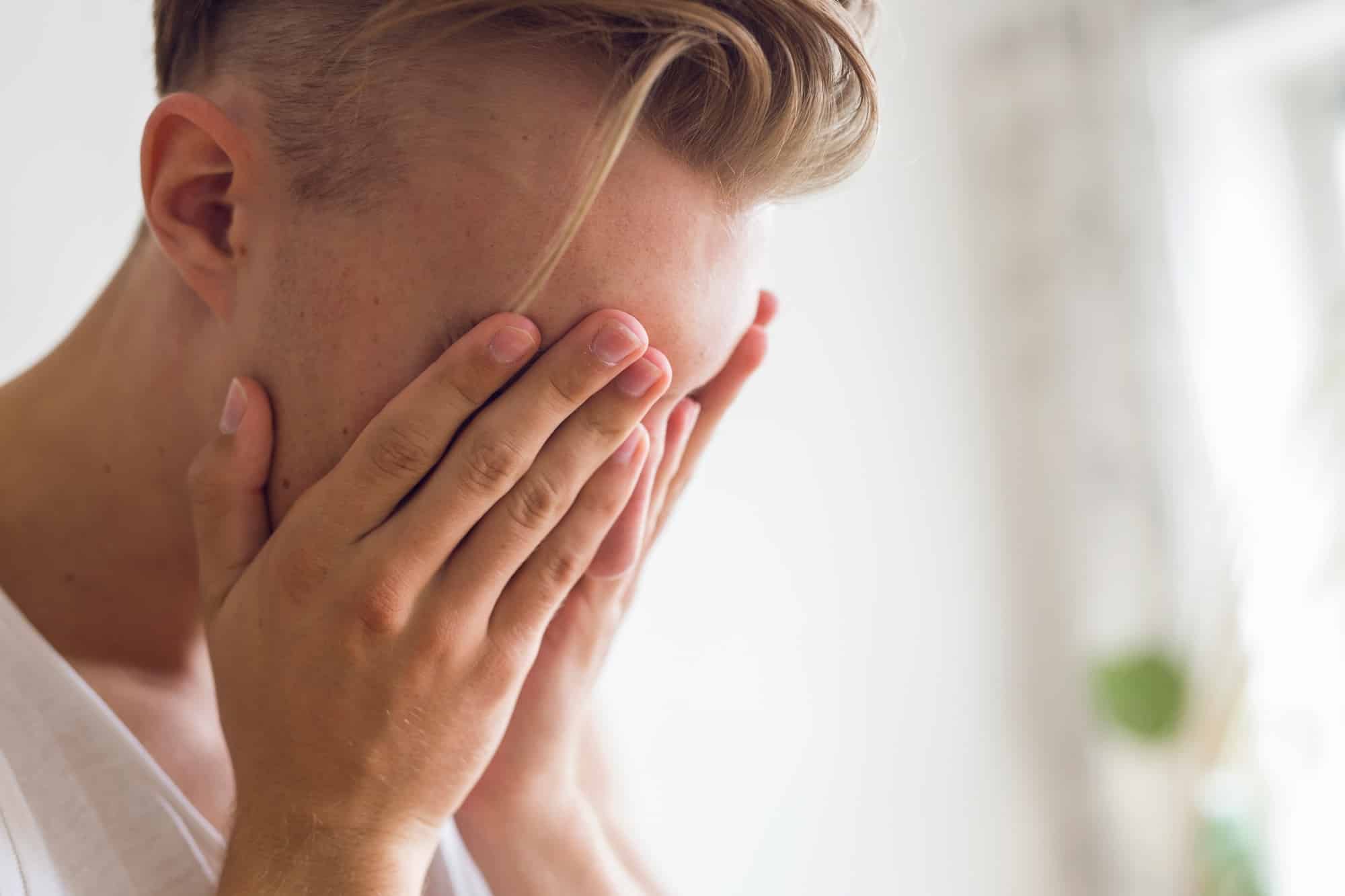 Pensive young man with head in hands