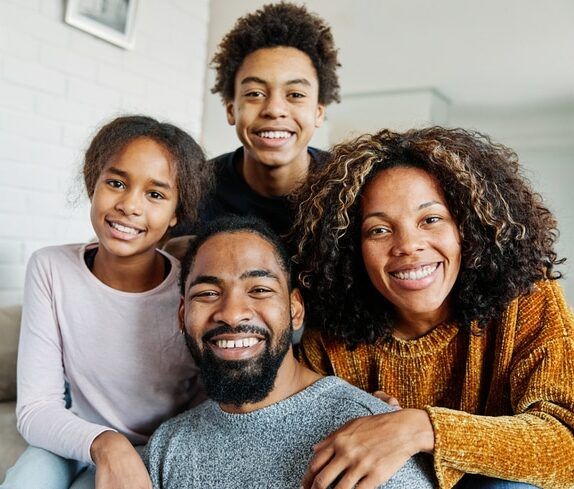 Portrait of a happy black family mother father and kids at home on couch